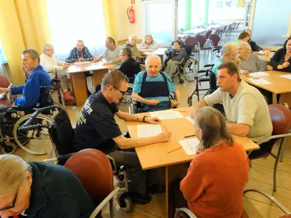 Mieszkańcy grają w bingo przy stolikach w świetlicy