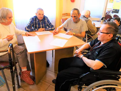 Mieszkańcy przy stole skreślają liczby na kartach do bingo