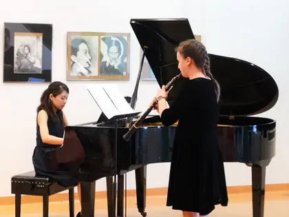 Pianistka przy fortepianie i oboistka grają koncert w galerii