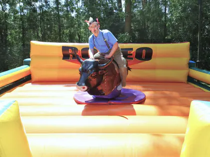 Mieszkaniec w kowbojskim kapeluszu jedzie na mechanicznym byku rodeo