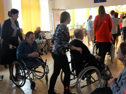 Goście pchają wózki z mieszkańcami w tanecznym korowodzie