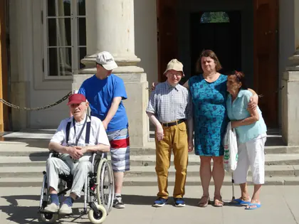 Mieszkańcy i opiekunki przed kolumnami pałacu w Łazienkach