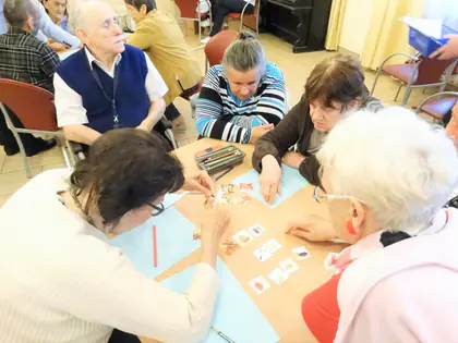 Mieszkańcy i seniorzy z fundacji układają obrazki przy wspólnym stole