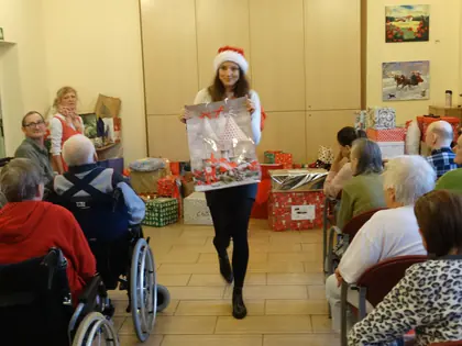 Dziewczyna w czapce Mikołaja niesie prezent do mieszkańców