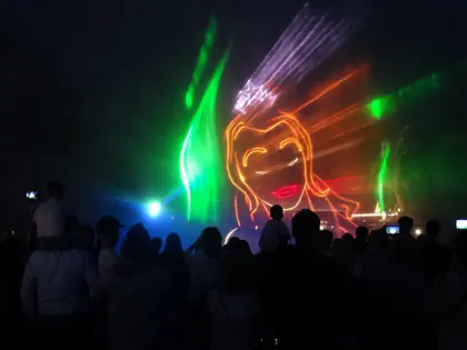 Laserowy pokaz w Multimedialnym Parku Fontann, z sylwetką syreny nad tłumem widzów