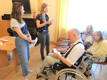 Dziewczyny czytają listy, mieszkaniec na wózku trzyma kartkę
