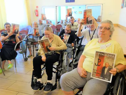 Mieszkańcy na wózkach trzymają egzemplarze magazynu Pokolenia ze znakiem Polski Walczącej