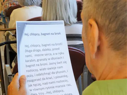 Mieszkaniec trzyma kartkę z tekstem piosenki „Hej, chłopcy, bagnet na broń”