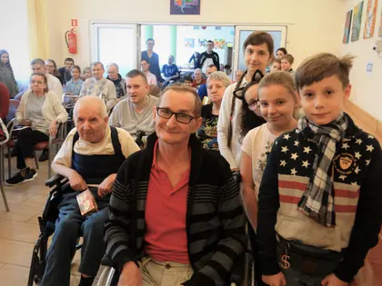 Mieszkańcy i dzieci ze szkoły podstawowej podczas wręczania świątecznych paczek