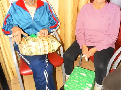 Mieszkaniec i mieszkanka z prezentami świątecznymi na kolanach