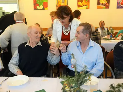 Mieszkańcy przy wigilijnym stole składają sobie życzenia z dyrektor