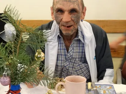 Mieszkaniec siedzi przy stole z kubkiem i świąteczną dekoracją