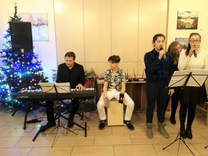 Zespół z keyboardem i cajonem, dwie wokalistki śpiewają przy choince
