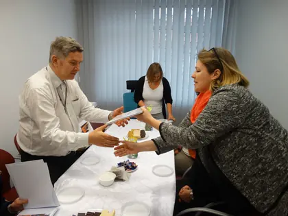Kobieta wręcza dyplom mężczyźnie przy stole