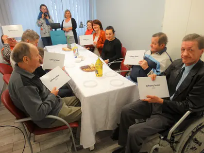 Mieszkańcy z dyplomami projektu „Cyfrowy Senior” przy stole z poczęstunkiem