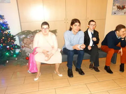 Czworo młodych osób siedzi na ławce przy choince