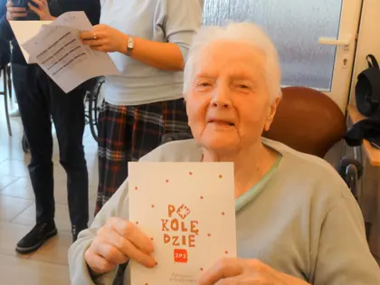 Starsza mieszkanka pokazuje broszurę z napisem Po kolędzie