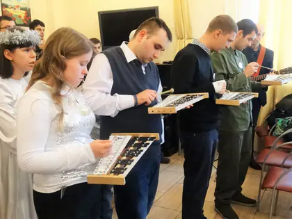 Młodzież gra na drewnianych cymbałkach podczas kolędowania