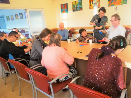 Uczestnicy zajęć przy stole z kolorowym papierem
