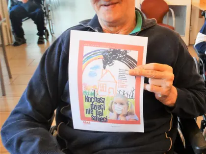 Mieszkaniec na wózku pokazuje plakat przeciw paleniu śmieci
