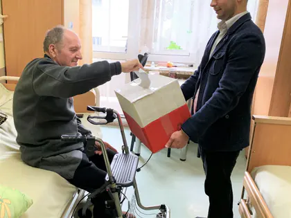 Mieszkaniec na łóżku głosuje do przenośnej urny