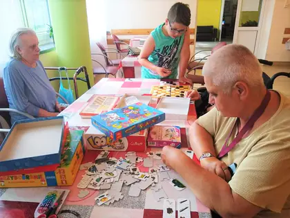 Mieszkańcy i chłopiec układają puzzle i grają w gry przy stole