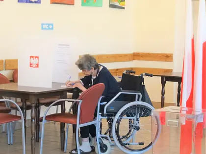 Mieszkanka na wózku wypełnia kartę do głosowania