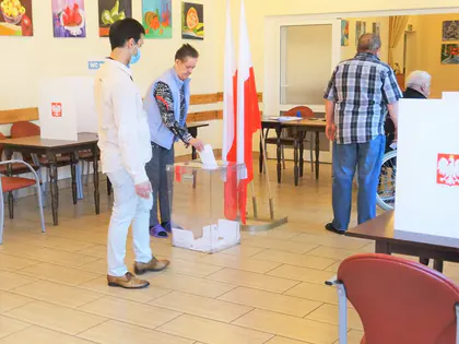 Mieszkaniec wrzuca kartę do urny w lokalu wyborczym w świetlicy