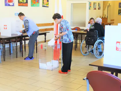 Lokal wyborczy w świetlicy Domu, mieszkańcy przy urnie i kabinach do głosowania
