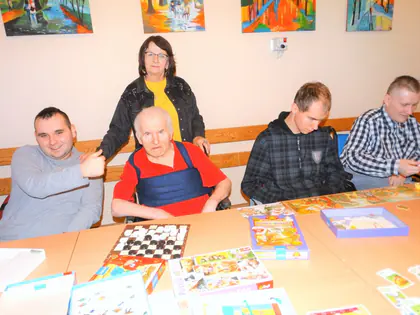 Mieszkańcy i opiekunka przy stole z grami planszowymi