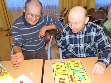Dwaj mieszkańcy przy stole grają w grę planszową podczas spotkania z uczniami