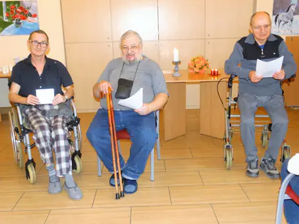 Trzech mieszkańców czyta wiersze siedząc przy stoliku ze świecą