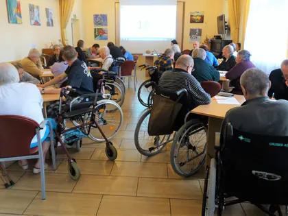 Świetlica pełna mieszkańców grających w bingo, na ekranie liczba