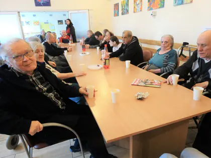 Mieszkańcy przy długim stole w świetlicy podczas ostatkowej biesiady