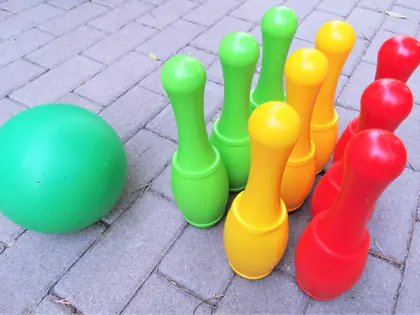 Kolorowe plastikowe kręgle i zielona kula na kostce brukowej