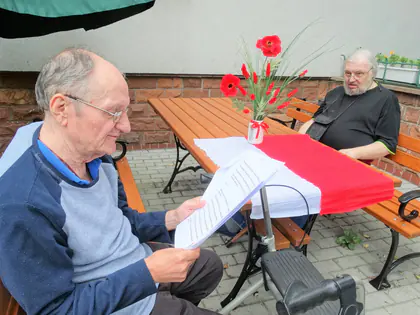 Mieszkaniec czyta tekst przy stole z biało-czerwoną flagą i makami