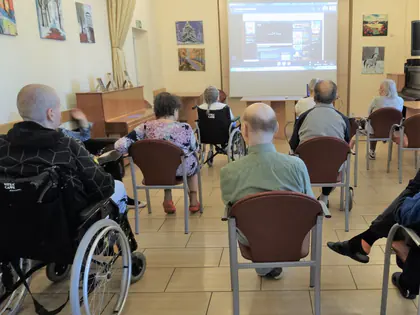 Mieszkańcy oglądają warsztaty online wyświetlane na ekranie w świetlicy