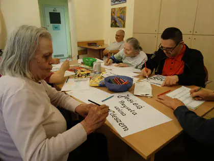 Mieszkanka pisze kaligraficzne litery na dużej kartce
