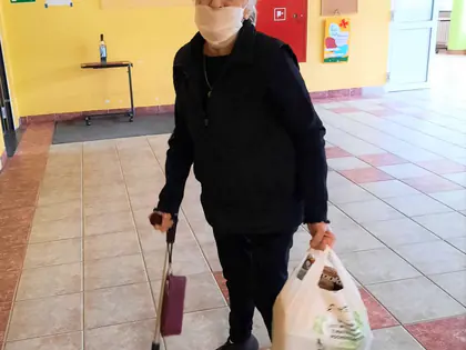 Mieszkanka z laską i siatką z zakupami wraca do Domu