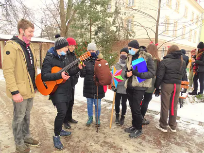 Kolędnicy z gitarą śpiewają na zaśnieżonym podwórku