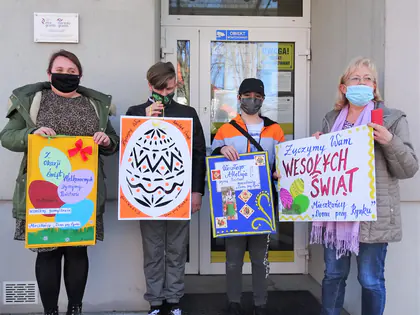 Młodzież z Domu przy Rynku trzyma przed wejściem do Domu plakaty z życzeniami Wesołych Świąt