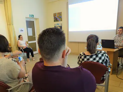 Pracownicy słuchają prelekcji w świetlicy, prelegent przy laptopie