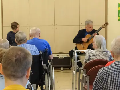 Gitarzysta gra przed mieszkańcami siedzącymi w sali