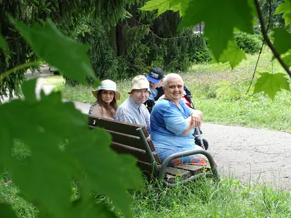 Mieszkańcy w kapeluszach siedzą na ławce w parku Traugutta