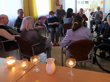 Mieszkańcy siedzą w półokręgu przy zapalonych świecach podczas treningu relaksacyjnego