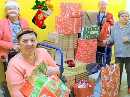 Mieszkańcy w czapkach Mikołaja przy stosie prezentów