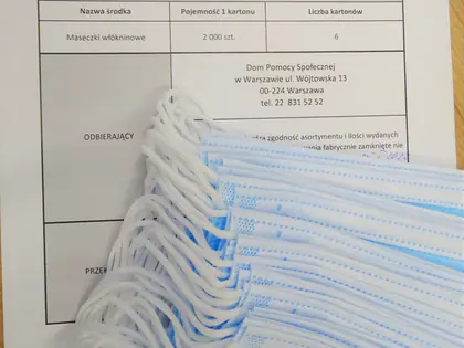 Protokół przekazania maseczek od Wojewody Mazowieckiego leżący obok paczki maseczek włókninowych