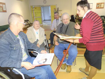 Prowadząca pokazuje książkę mieszkańcom siedzącym w kręgu