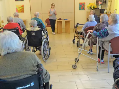 Mieszkańcy na wózkach słuchają prelekcji