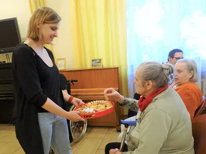 Wolontariuszka częstuje mieszkanki ciasteczkami z tacy